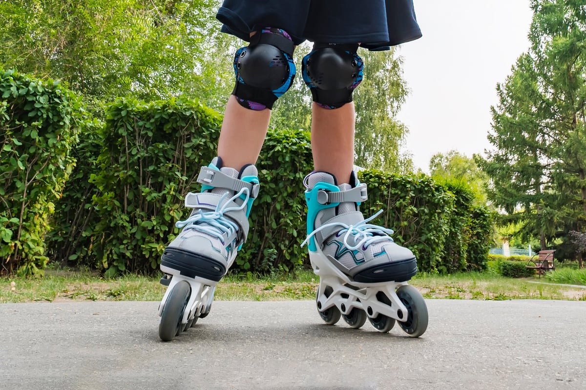 Closeup view of white roller skates or rollerblading. Roller skate legs of a child in park. Girl legs in roller blades.