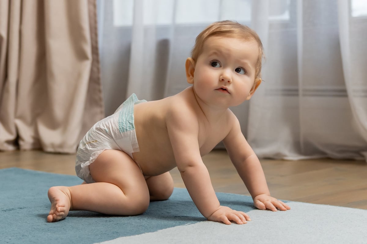 Cute little baby boy crawling on the floor and looking contented