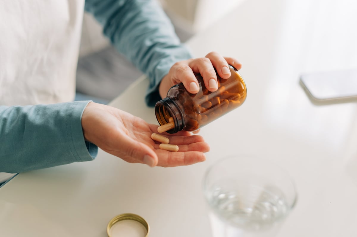 Close-up of an unrecognizable woman's hands holding a jar of capsules. Health concept.