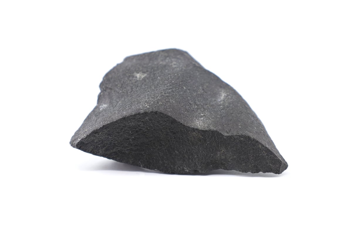 Piece of raw Shungite, semi precious stone used as crystal healing, on white background