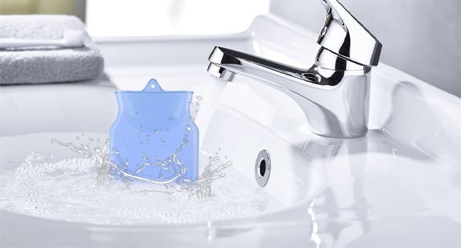 Blue toothbrush holder splashing in water at bathroom sink with chrome faucet